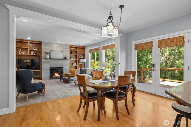 dining space with french doors, a tiled fireplace, light wood-type flooring, and recessed lighting