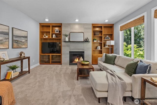 living room featuring light carpet, a fireplace, recessed lighting, baseboards, and built in features