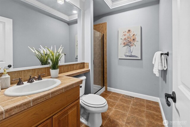 bathroom featuring ornamental molding, a stall shower, toilet, baseboards, and vanity