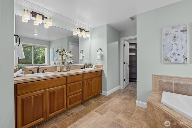 full bath featuring a garden tub, double vanity, stone tile flooring, and baseboards