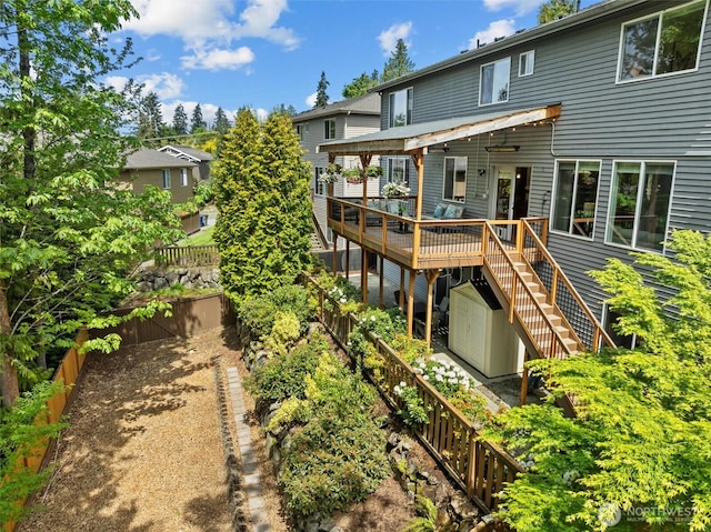back of property with stairway, a wooden deck, and fence