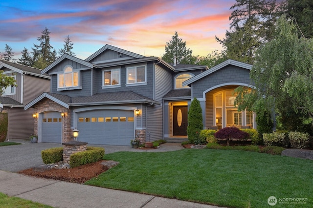 craftsman house with driveway, an attached garage, stone siding, and a lawn