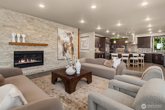 living room featuring light wood finished floors, a stone fireplace, and recessed lighting
