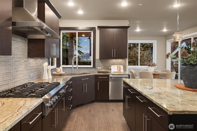 kitchen with recessed lighting, a sink, wall chimney exhaust hood, decorative backsplash, and stainless steel appliances