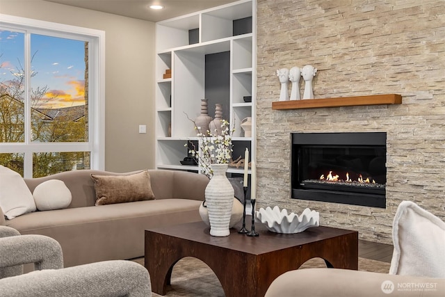 living room featuring built in shelves, a healthy amount of sunlight, a fireplace, and wood finished floors