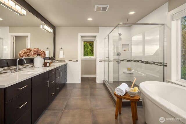 full bath featuring a sink, a soaking tub, double vanity, and a shower stall