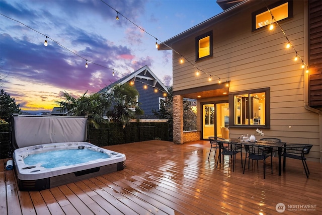 deck at dusk with hot tub deck surround and outdoor dining space