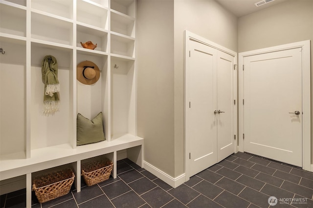 mudroom with dark tile patterned floors, visible vents, and baseboards