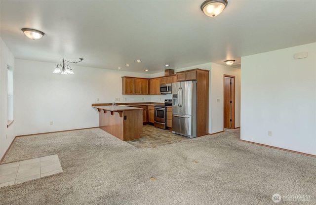 kitchen with appliances with stainless steel finishes, light carpet, baseboards, brown cabinetry, and a peninsula