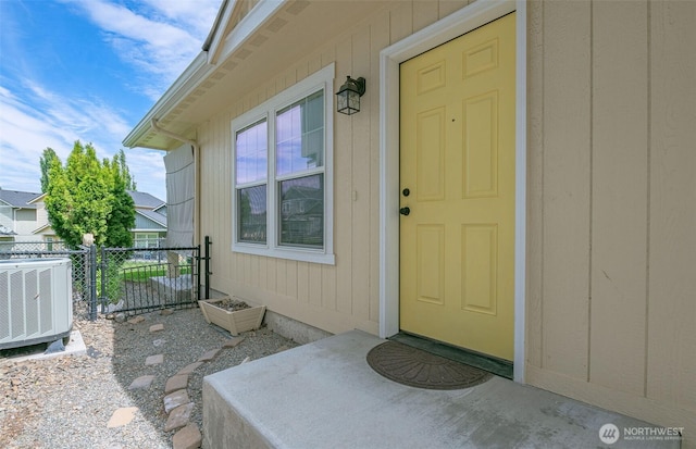 entrance to property featuring central AC unit and fence