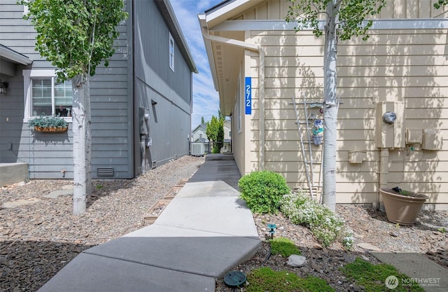 exterior space with board and batten siding, electric meter, and central air condition unit