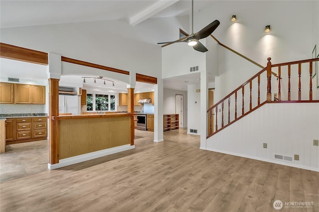 1002 30th St NE, Auburn, WA 98002 - unfurnished living room featuring ornate columns, ceiling fan, light wood-style flooring, beamed ceiling, and high vaulted ceiling