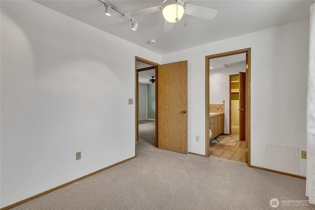 1002 30th St NE, Auburn, WA 98002 - unfurnished bedroom with light carpet, rail lighting, baseboards, ensuite bath, and ceiling fan