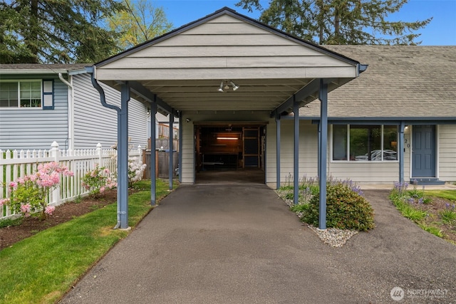 view of front of house with fence, driveway, and roof with shingles