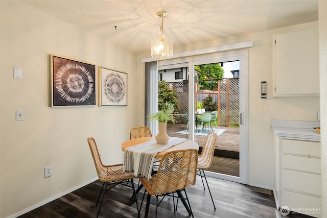 dining area featuring a chandelier, wood finished floors, baseboards, and a textured ceiling