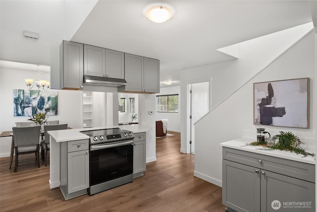 4822 S M St, Tacoma, WA 98408 - kitchen with gray cabinets, stainless steel electric stove, under cabinet range hood, and a chandelier