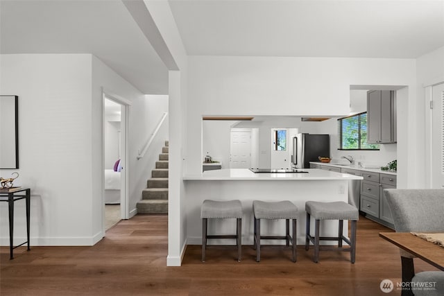 4822 S M St, Tacoma, WA 98408 - kitchen with gray cabinetry, freestanding refrigerator, a sink, a breakfast bar area, and light countertops