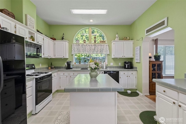 kitchen with black appliances, light floors, and white cabinets