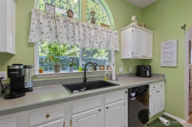 kitchen featuring dishwasher, white cabinetry, and a sink