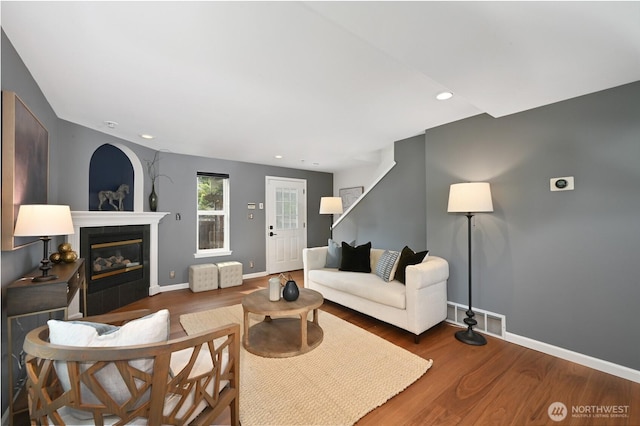 living room featuring wood finished floors, a tile fireplace, baseboards, and recessed lighting