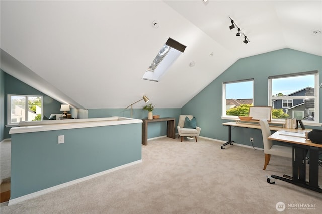 office space featuring lofted ceiling, carpet floors, track lighting, baseboards, and a skylight