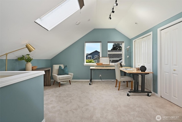 carpeted office with lofted ceiling, a skylight, rail lighting, and baseboards