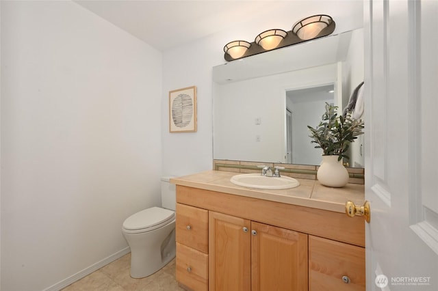 bathroom with vanity, toilet, tile patterned flooring, and baseboards