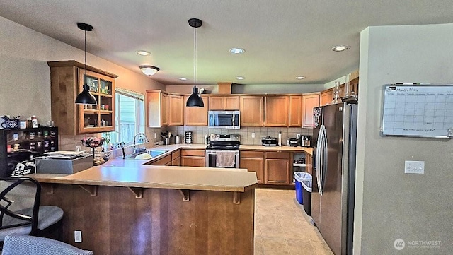 kitchen with stainless steel appliances, a sink, a peninsula, backsplash, and light countertops