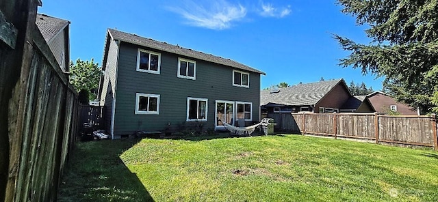 back of house with a lawn and a fenced backyard