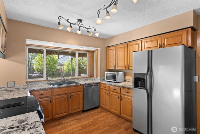 2350 38th Ave, Longview, WA 98632 - kitchen with appliances with stainless steel finishes, a sink, light stone countertops, light wood-style floors, and a textured ceiling