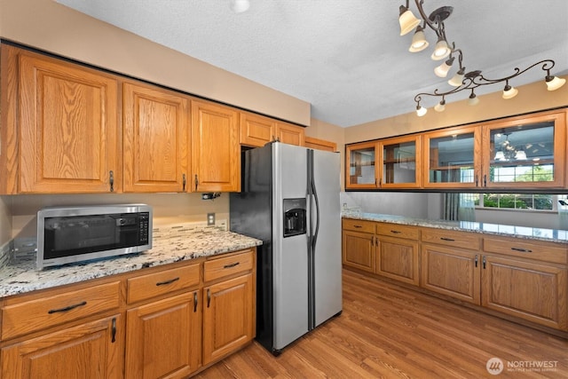 2350 38th Ave, Longview, WA 98632 - kitchen with appliances with stainless steel finishes, brown cabinetry, light wood-style flooring, glass insert cabinets, and a textured ceiling