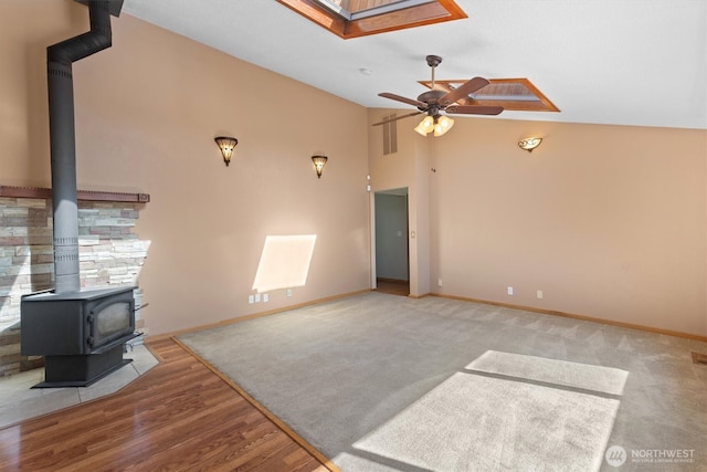 2350 38th Ave, Longview, WA 98632 - unfurnished living room with a wood stove, ceiling fan, a skylight, baseboards, and vaulted ceiling