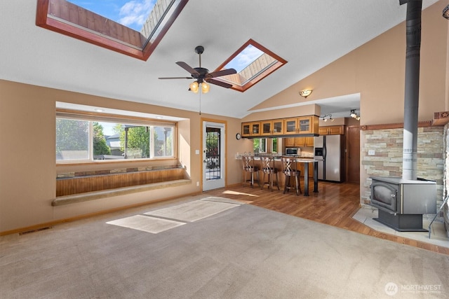 2350 38th Ave, Longview, WA 98632 - carpeted living area with a wood stove, a skylight, a ceiling fan, high vaulted ceiling, and baseboards