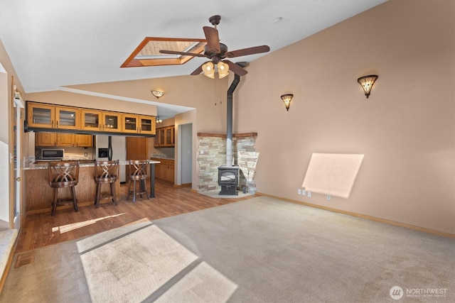 2350 38th Ave, Longview, WA 98632 - living room with ceiling fan, a wood stove, light carpet, baseboards, and high vaulted ceiling