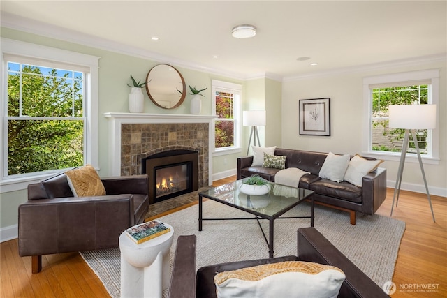 living area with wood finished floors, plenty of natural light, a fireplace with flush hearth, and ornamental molding
