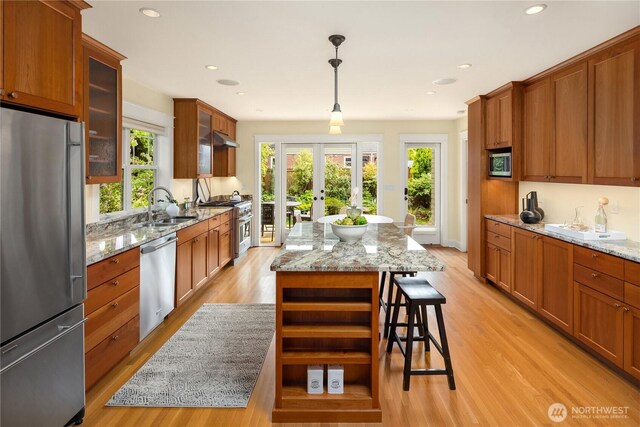 kitchen featuring appliances with stainless steel finishes, a sink, light wood-style floors, glass insert cabinets, and recessed lighting