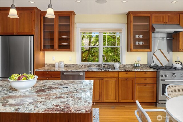 kitchen featuring appliances with stainless steel finishes, a sink, under cabinet range hood, recessed lighting, and light stone countertops