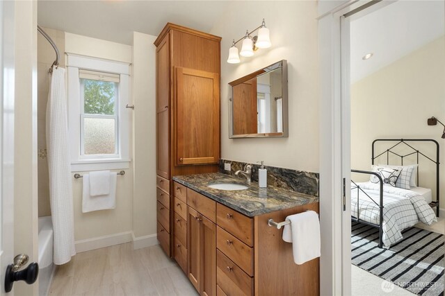 full bath featuring vanity, shower / bath combo with shower curtain, and baseboards