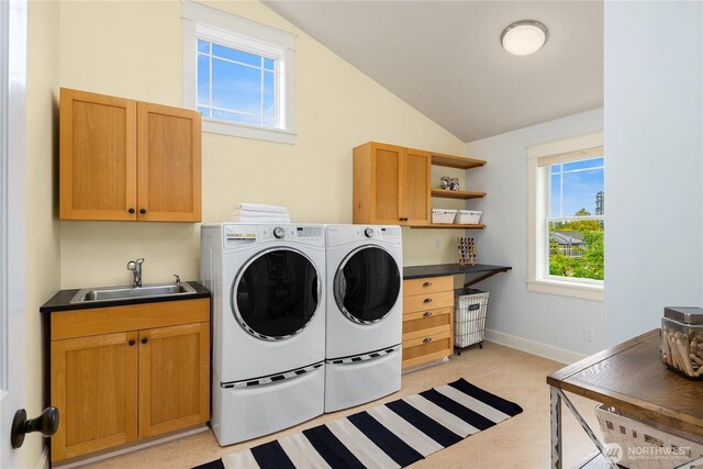 washroom featuring separate washer and dryer, cabinet space, baseboards, and light floors