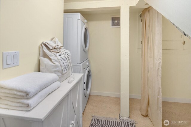 washroom featuring stacked washer / drying machine and baseboards