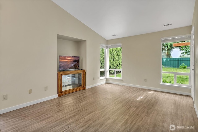 1004 30th St NE, Auburn, WA 98002 - unfurnished living room with vaulted ceiling, wood finished floors, baseboards, and plenty of natural light
