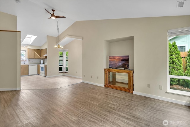 1004 30th St NE, Auburn, WA 98002 - unfurnished living room with a skylight, a chandelier, healthy amount of natural light, lofted ceiling, and ceiling fan