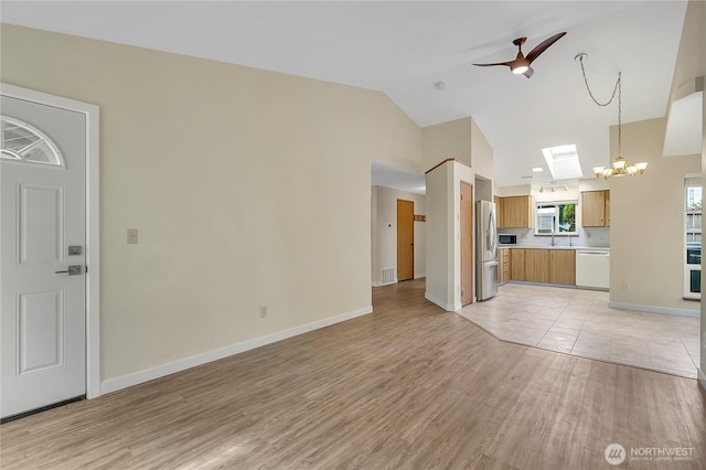 1004 30th St NE, Auburn, WA 98002 - unfurnished living room with light wood-style floors, a ceiling fan, a chandelier, high vaulted ceiling, and baseboards