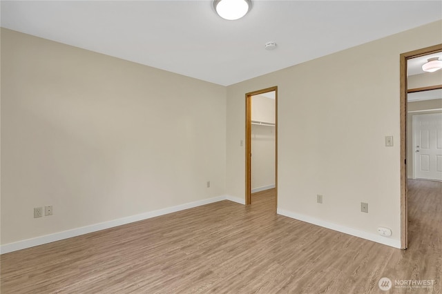 1004 30th St NE, Auburn, WA 98002 - unfurnished bedroom featuring light wood-type flooring, baseboards, a spacious closet, and a closet