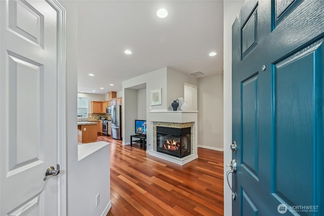 entryway with a multi sided fireplace, dark wood-style floors, recessed lighting, and baseboards