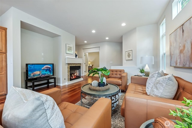 living area with wood finished floors, a glass covered fireplace, and recessed lighting
