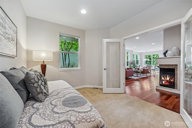 carpeted bedroom featuring recessed lighting, baseboards, and a multi sided fireplace