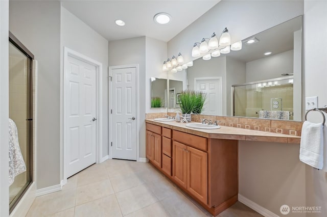 bathroom with a stall shower, tile patterned flooring, double vanity, and baseboards