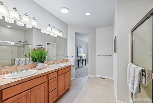 full bathroom with a stall shower, double vanity, tile patterned floors, baseboards, and recessed lighting