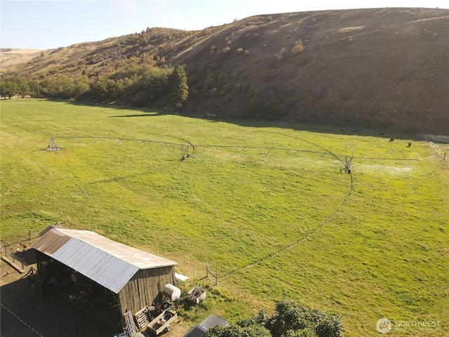 view of yard featuring a pole building, an outdoor structure, a rural view, and a mountain view